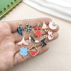 Hand holding assorted enamel alloy pendants including clover, flowers, and heart shapes
