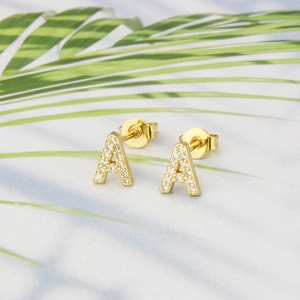 Macro shot of gold-plated letter A stud earrings with sparkling cubic zirconia on leaves