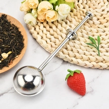 Close-up of a stainless steel tea infuser with mesh ball on a marble surface background