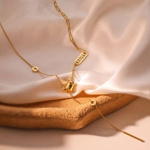 Goldene Titanstahl-Halskette mit HAPPY-Anhänger auf edlem Seiden- und Steinsockel
