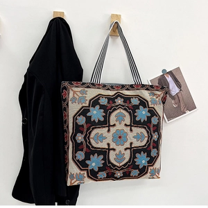 Close-up of vintage floral embroidery and striped strap on ethnic canvas tote bag