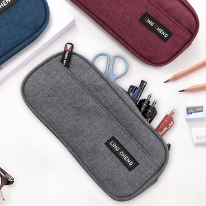 Large capacity oxford fabric pencil case in grey and burgundy with stationery on white desk