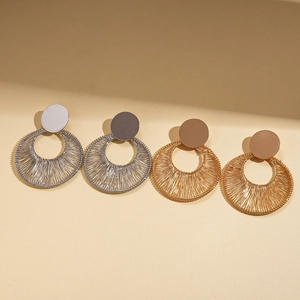 Golden and silver wire-wrapped circular hollow earrings set on a textured background