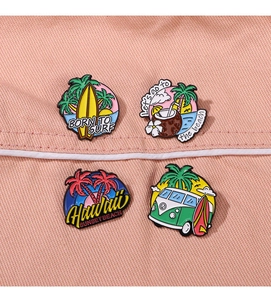 Detail of colorful enamel pins with summer beach motifs on pink fabric background