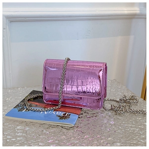 Detail of pink metallic crocodile pattern crossbody bag with a silver chain strap