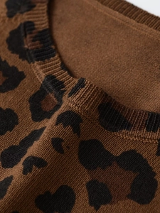 Detailed close-up of leopard print knit sweater showing ribbed crew neck and soft texture