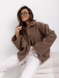 Détail du tissu en laine marron avec boutonnière simple et grande poche sur la veste