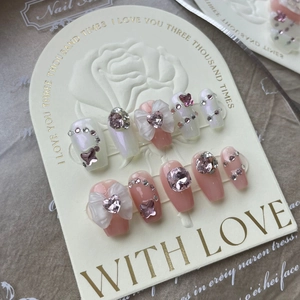 Detailed macro view of handmade press-on nails with 3D bows and pink crystal rhinestones