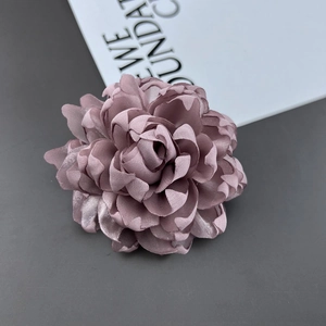 Detail of multi-layered fabric flower pin with 3D petals in a dusty rose silk finish