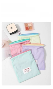 Flat lay of colorful macaron makeup bags with zippers and woven labels on white background