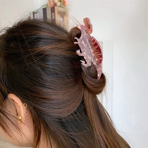 Detail of pink marble acrylic dinosaur hair claw clip styled on dark brown long hair