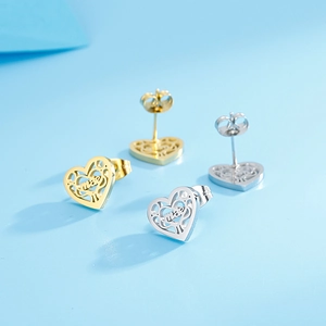 Détail de boucles d'oreilles cœur évidées en or et argent avec gravure mae unique
