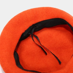 Detail view of the orange wool pumpkin beret interior with black sweatband and drawstrings