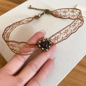 Detailed close-up of brown lace choker necklace with a vintage gold heart-shaped pendant