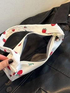 Close-up of strawberry print nylon bag with gold zipper and grey interior lining