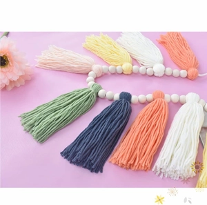 Detail of colorful cotton tassels and natural wooden beads on a bohemian wall hanging