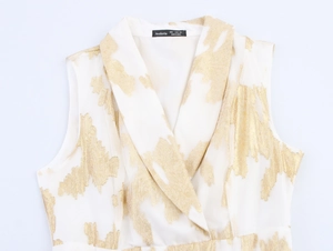 Détail du tissu blanc avec texture dorée abstraite et col en V sur une robe élégante