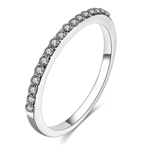 Détail d'une bague d'éternité en argent avec une rangée de cristaux brillants sur fond blanc