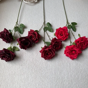 Flat lay of artificial 3-head diamond roses in red and wine red on beige textile
