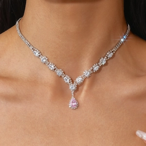Close-up of elegant V-shape silver necklace with pink teardrop zircon on female neck