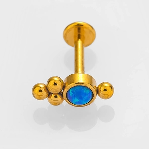 Macro detail of gold 316L stainless steel labret stud with blue opal stone and sphere accents