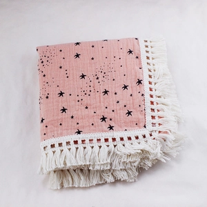 Detail of soft pink cotton baby swaddle with black star prints and white fringe tassels