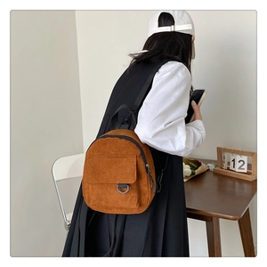 Detail of retro caramel corduroy backpack featuring ribbed texture and metal D-ring closure