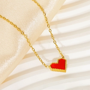 Macro shot of 18k gold necklace featuring a red heart pendant with beaded edge detail