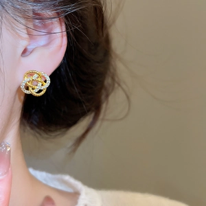 Gros plan de boucles d'oreilles fleur évidée dorée avec zircon sur un modèle pour un look chic