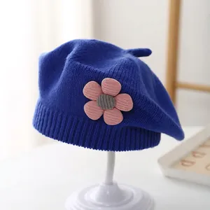 Detail of blue knitted beret for girls featuring a 3D pink flower and soft yarn texture
