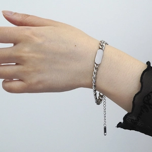 Detail of silver stainless steel Cuban link bracelet with engravable nameplate on wrist