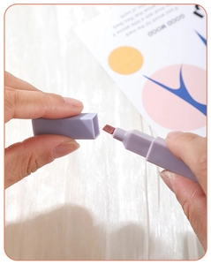 Close-up of hands opening a lavender dual-tip highlighter with visible fiber nib texture