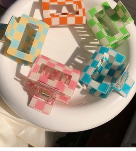 Detailed top view of five colorful checkerboard hair claws arranged on a white plate