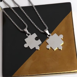 Close-up of interlocking puzzle pendant necklaces in silver-toned polished stainless steel
