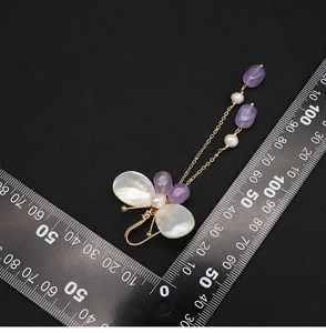 Detailed view of long butterfly pearl earrings with scale showing 75mm length