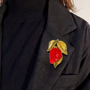 Red strawberry enamel brooch with gold leaves pinned on a black suit jacket lapel