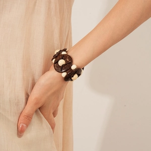 Detail of bohemian geometric coconut shell and wood bead stretch bracelet on a wrist