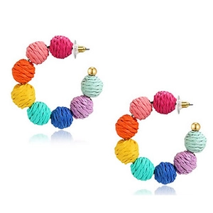 Detailed view of colorful woven ball hoop earrings with golden studs on white backdrop