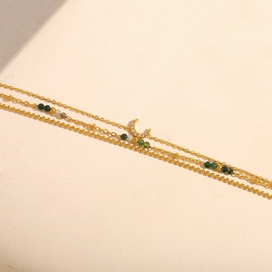 Detailed close-up of 18K gold-plated triple-layer bracelet with moon charm and gems