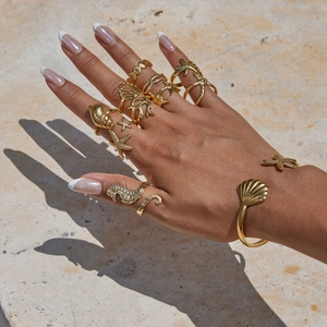 Golden ocean series jewelry set with shell and starfish rings on marble surface