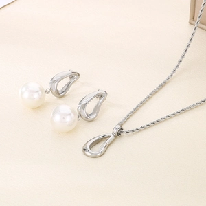 Close-up of pearl jewelry set with irregular metal rings on textured beige fabric