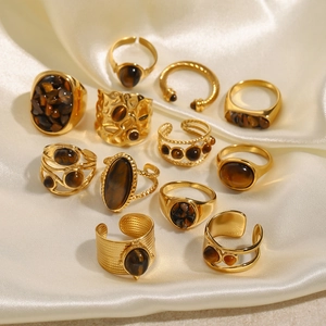 Makro-Ansicht von 11 Vintage Gold Edelstahlringen mit Tigerauge-Steinen auf Seide