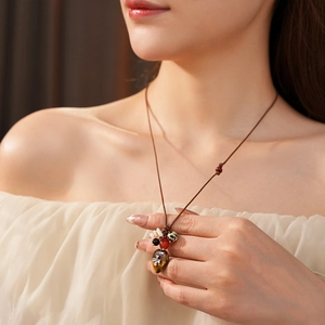 Detail of bohemian necklace with wax cord, colorful beads, and silver cross on gemstone