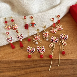 Détail de boucles d'oreilles danse du lion avec pompons rouges et breloques porte-bonheur