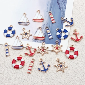 Flat lay of nautical alloy enamel charms featuring anchor lighthouse and sailboat designs