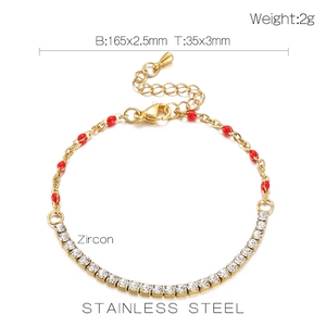 Macro shot of gold stainless steel bracelet detailing dimensions with red bead and zircon