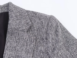 Detail of grey herringbone blazer showing textured shoulder seams and lapel quality