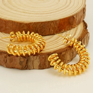 Modern C-shaped spring earrings in gold-plated stainless steel on a wooden base