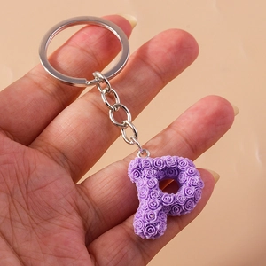 Detailed macro view of a purple rose-textured letter P keychain held in hand