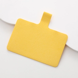Dettaglio macro della linguetta per cordino in microfibra gialla con anello a D su base bianca